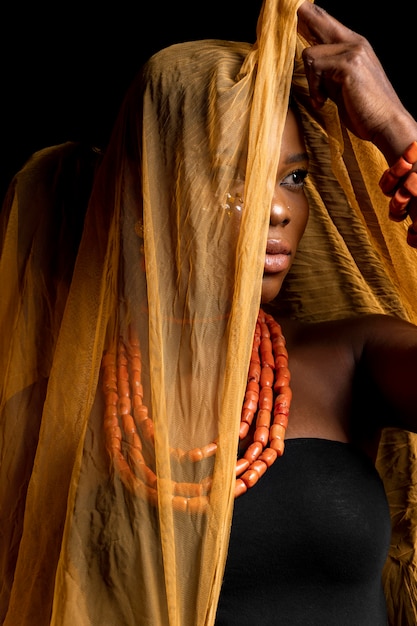 Porträt der afrikanischen Frau, die traditionelle Accessoires und gelben Schleier trägt