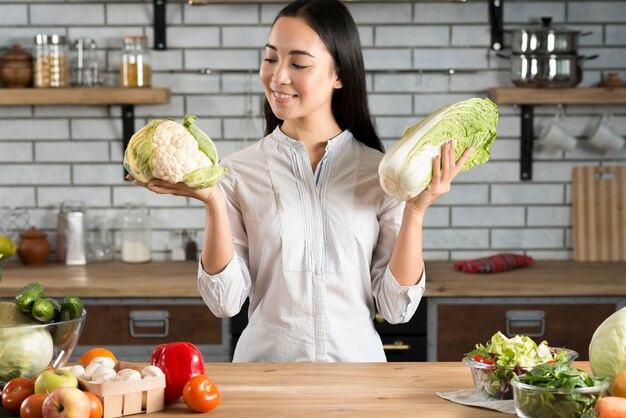 Porträt der asiatischen Frau grünen Blumenkohl und Kopfsalat in der Küche halten