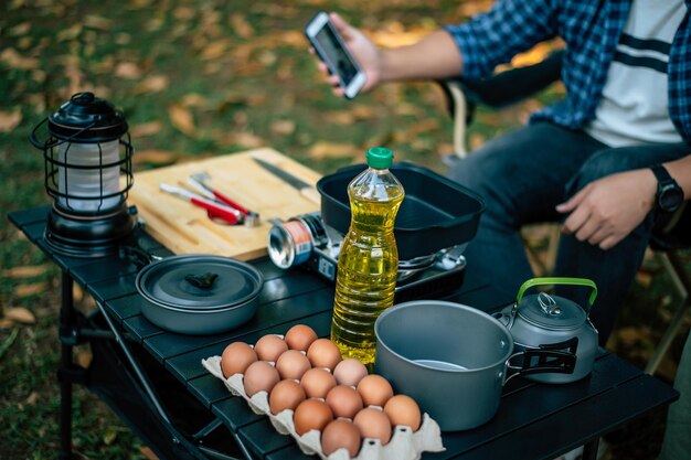 Porträt der asiatischen Mannbrille, die auf dem Campingplatz kocht Outdoor-Kochen beim Camping-Lifestyle-Konzept