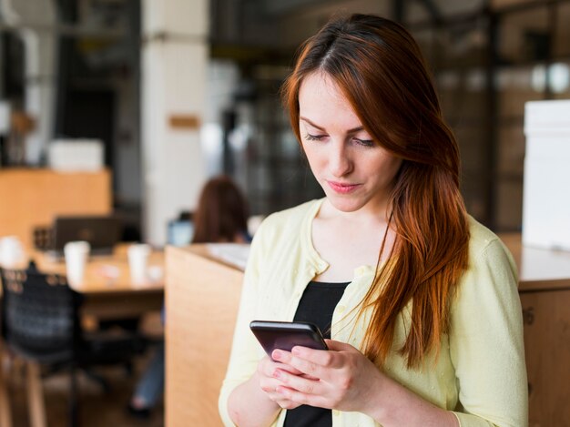 Porträt der attraktiven jungen Frau, die Smartphone verwendet