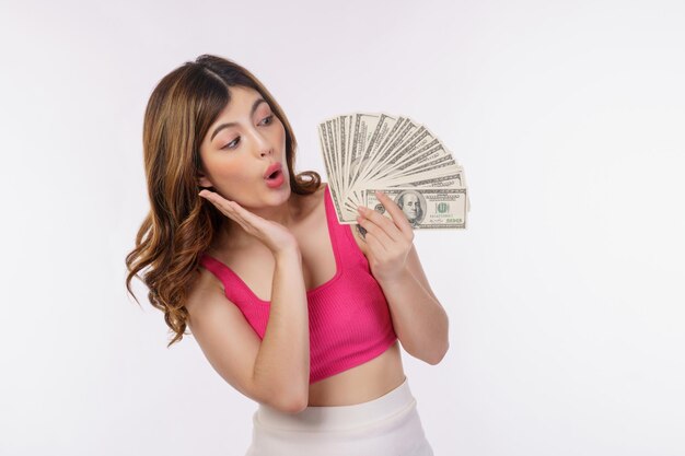 Porträt der aufgeregten jungen Frau, die Bündel Dollarbanknoten lokalisiert über weißem Hintergrund hält