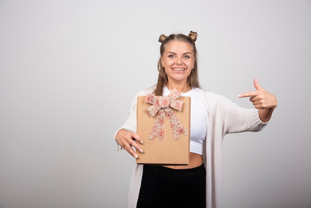 Porträt der blonden Frau auf Geschenkbox zeigend.