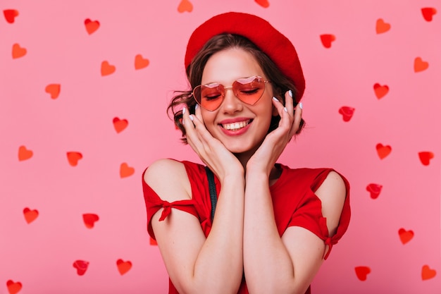 Porträt der entspannten attraktiven Frau, die am Valentinstag genießt. Innenfoto des ansprechenden europäischen Mädchens mit dunklem welligem Haar.