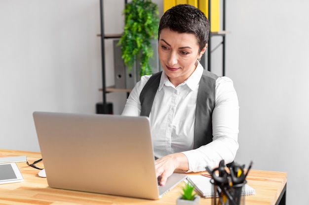 Kostenloses Foto porträt der erwachsenen frau, die am laptop arbeitet