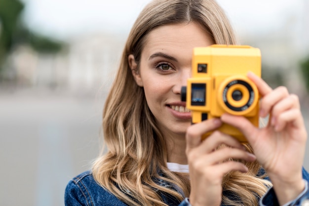 Porträt der Frau, die eine Retro gelbe Kamera hält