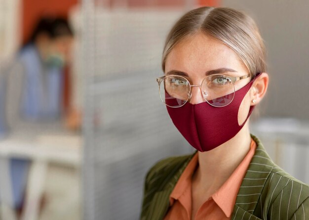 Porträt der Frau, die Gesichtsmaske bei der Arbeit trägt