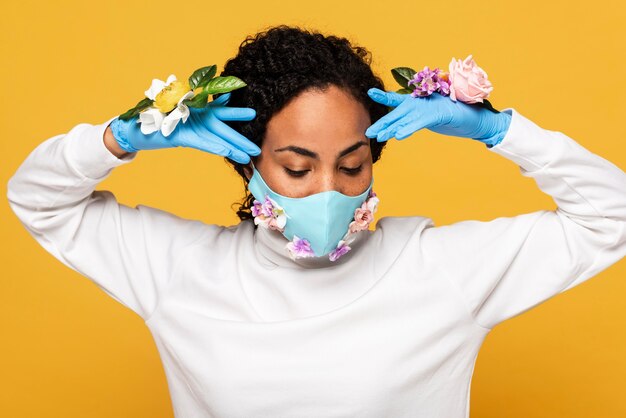 Porträt der Frau, die mit Blumenmaske und Handschuhen aufwirft