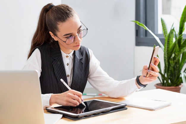 Porträt der Frau, die mit mehreren Geräten arbeitet