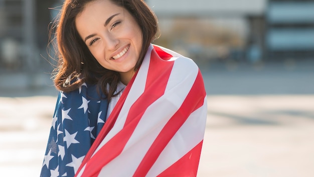 Porträt der Frau, die sich in USA-Flagge einwickelt