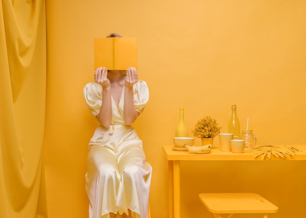 Kostenloses Foto porträt der frau ein buch in einer gelben szene lesend