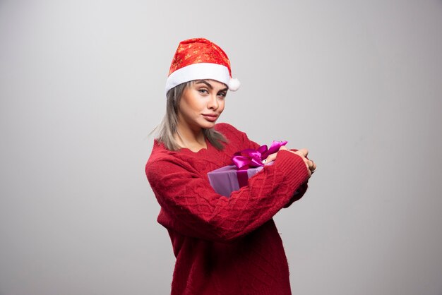 Porträt der Frau mit der Geschenkbox, die auf grauem Hintergrund steht.