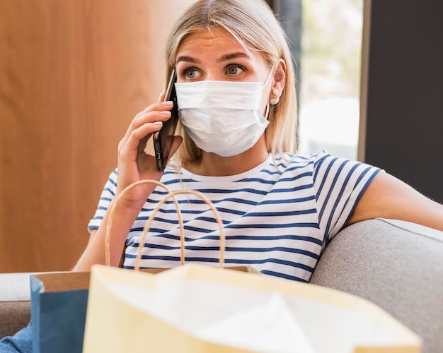 Porträt der Frau mit der Gesichtsmaske, die am Telefon spricht