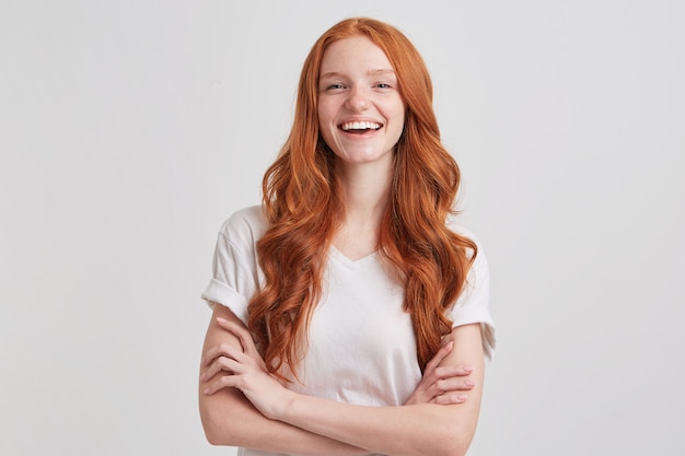 Kostenloses Foto porträt der fröhlichen niedlichen rothaarigen jungen frau mit langen gewellten haaren