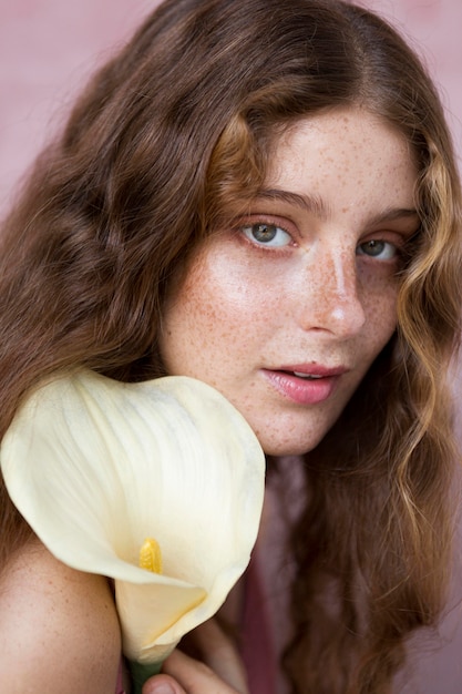 Kostenloses Foto porträt der geheimnisvollen sommersprossigen frau, die eine blume hält