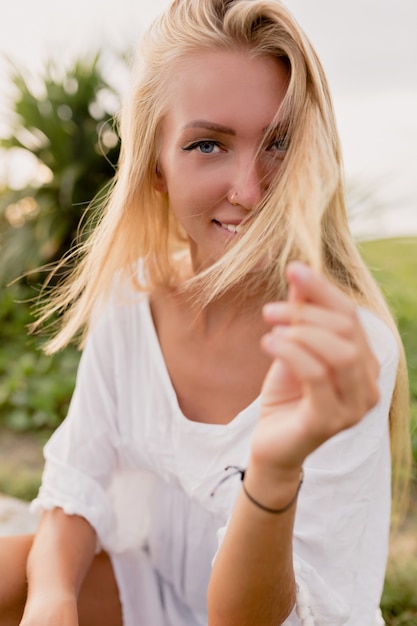 Porträt der glücklichen aufgeregten jungen Frau mit offenem Blick, der mit ihren Haaren spielt