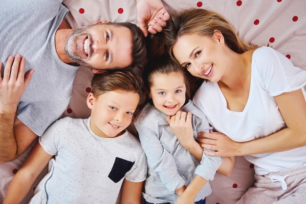 Porträt der glücklichen familie, die auf dem bett liegt Kostenlose Fotos