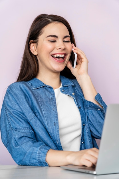 Porträt der glücklichen Frau, die am Telefon spricht und Laptop verwendet