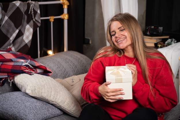 Porträt der glücklichen Frau, die Geschenkbox auf Bett hält.