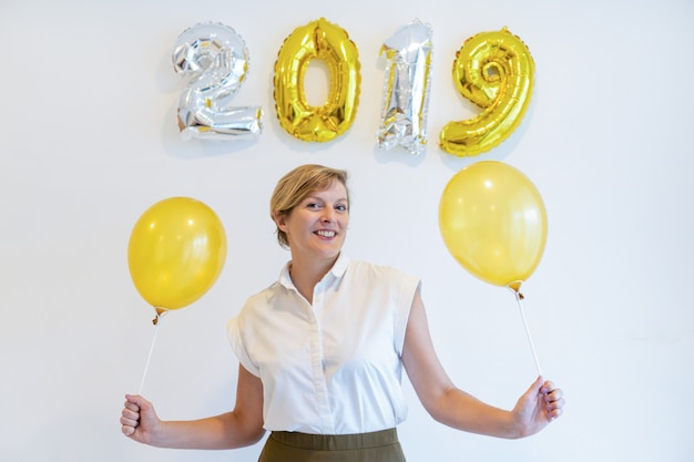 Porträt der glücklichen Frau stehend mit Ballonen unter Zeichen 2019