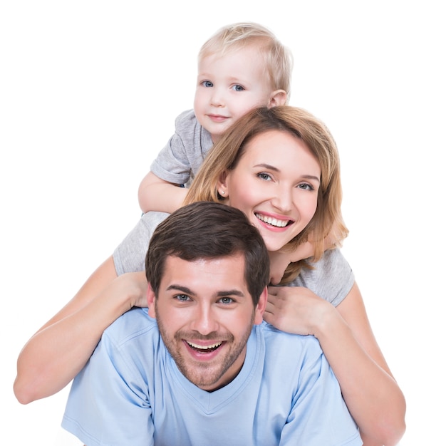 Porträt der glücklichen jungen Familie mit den auf dem Boden liegenden Kindern - isoliert