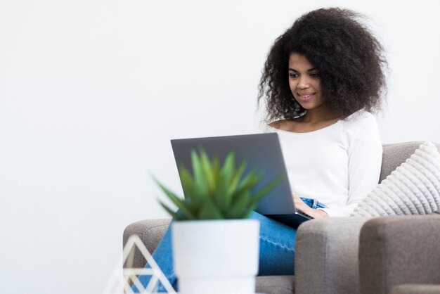 Porträt der glücklichen jungen Frau, die an einem Laptop arbeitet