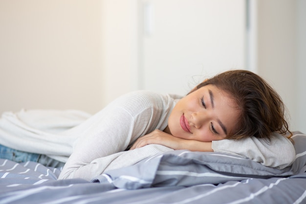 Porträt der glücklichen jungen Frau, die im Bett schläft