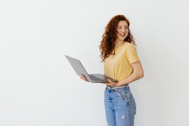 Porträt der glücklichen jungen Frau, die Laptop auf einem weißen Hintergrund hält