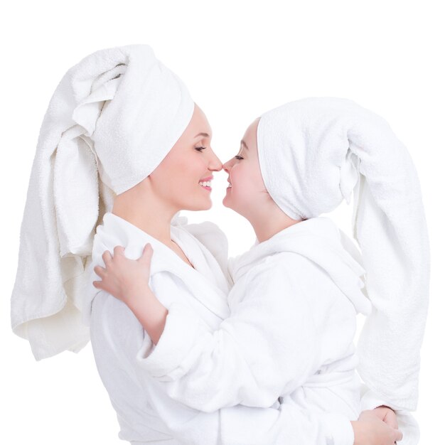 Porträt der glücklichen Mutter und der kleinen Tochter im weißen Bademantel sehen sich an - isoliert