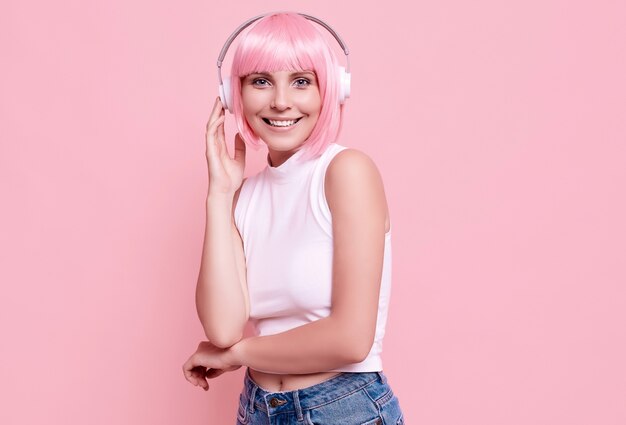 Porträt der herrlichen Frau mit rosa Haaren genießt die Musik in Kopfhörern
