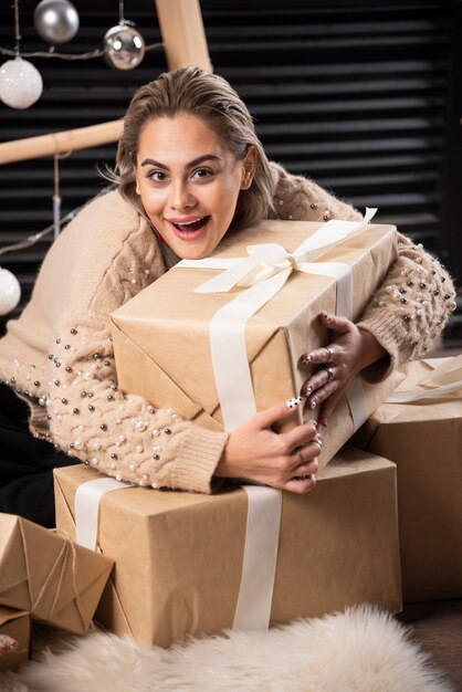 Porträt der hübschen Frau, die eine Schachtel Weihnachtsgeschenk umarmt