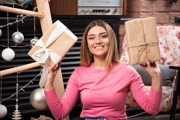 Kostenloses Foto porträt der hübschen frau, die weihnachtsgeschenke sitzt und hält.