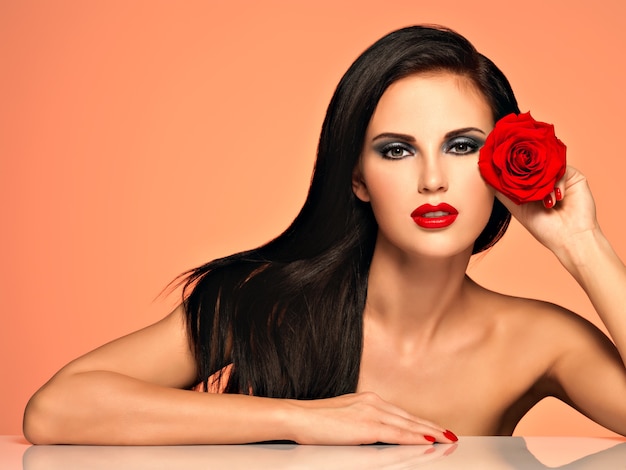 Porträt der hübschen schönen Frau mit hellem Mode-Make-up hält rote Rose