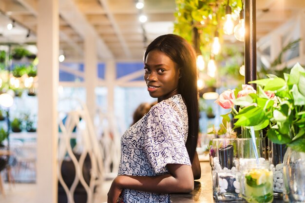 Porträt der jungen afrikanischen Frau, die im Café steht