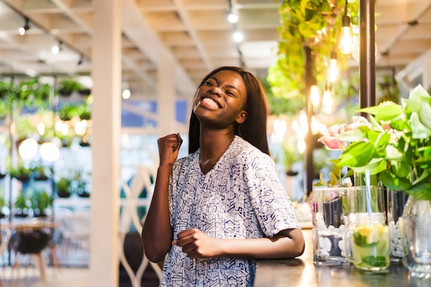 Porträt der jungen afrikanischen Frau, die im Café steht