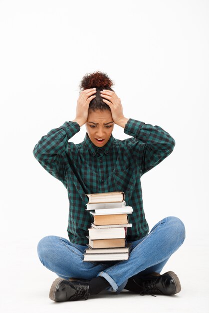 Porträt der jungen afrikanischen Frau mit Büchern auf Weiß.