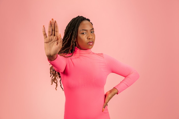 Porträt der jungen afroamerikanischen Frau isoliert auf rosa Studio, Gesichtsausdruck.