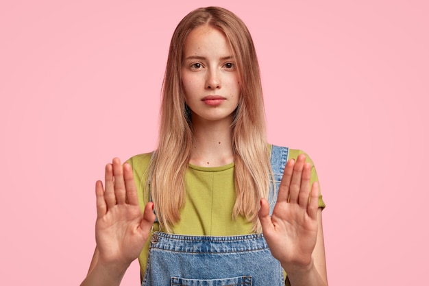 Kostenloses Foto porträt der jungen blonden frau, die jeansoveralls trägt