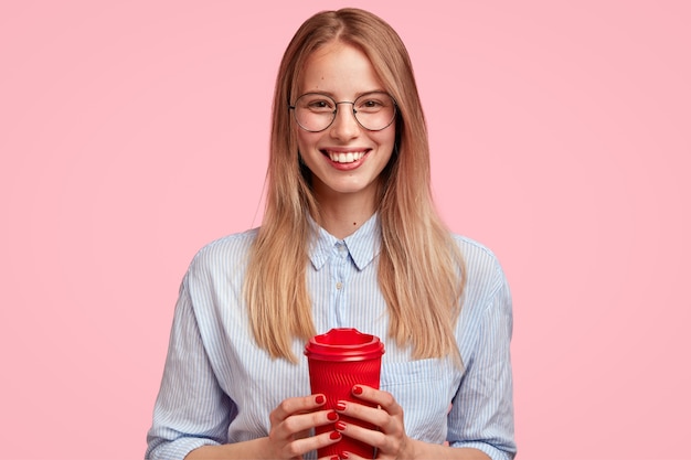 Porträt der jungen blonden Frau, die Tasse Kaffee hält