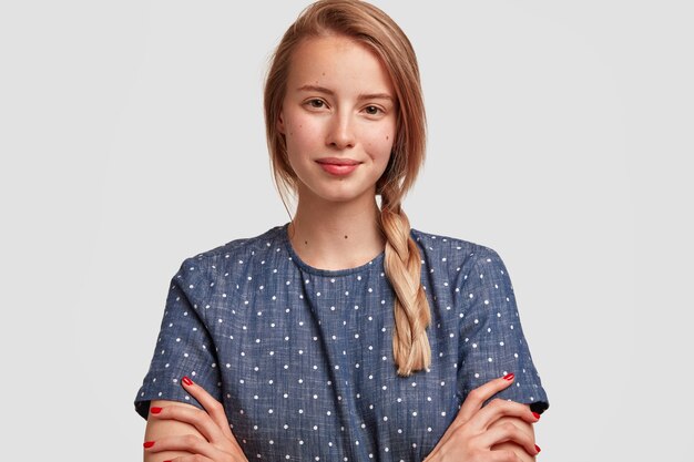 Porträt der jungen blonden Frau mit Zopf und gepunkteter Bluse