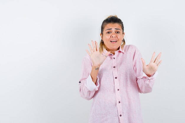 Porträt der jungen Dame, die Stoppgeste in rosa Hemd zeigt und erschreckte Vorderansicht schaut