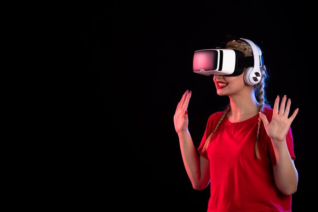 Porträt der jungen Dame, die vr in Kopfhörern auf dunklem Visual spielt