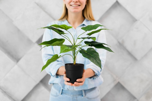 Kostenloses Foto porträt der jungen frau, die eine pflanze hält