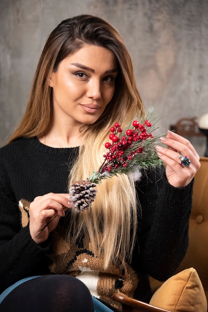 Porträt der jungen Frau, die einen Zweig der Weihnachtsstechpalmenbeeren hält. Hochwertiges Foto
