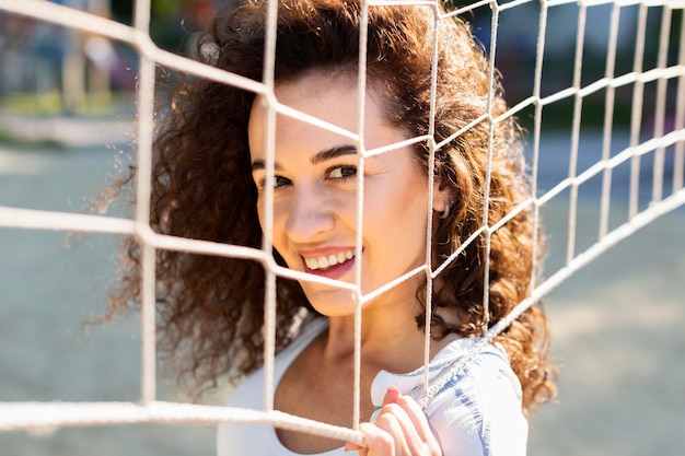 Porträt der jungen Frau, die neben einem Volleyballfeld aufwirft