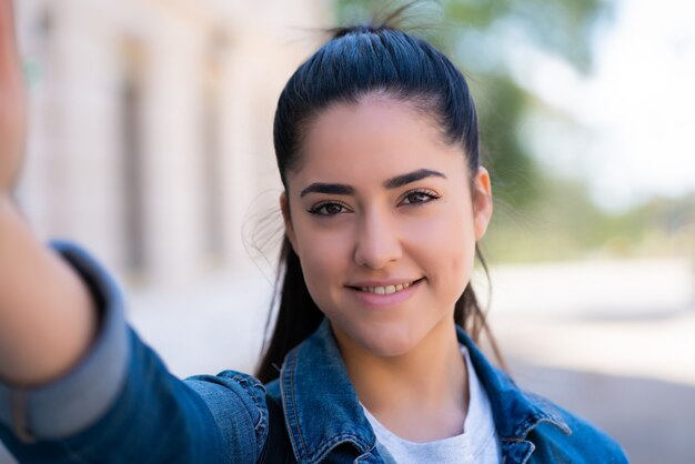 Porträt der jungen Frau, die selfies nimmt, während sie draußen auf der Straße steht