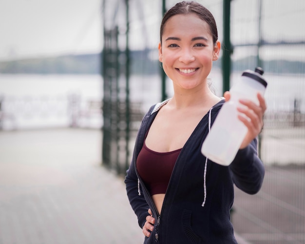 Porträt der jungen Frau, die Wasserflasche hält