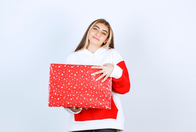 Porträt der jungen Frau im warmen Hoodie mit Weihnachtsgeschenk