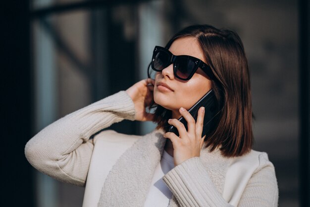 Porträt der jungen Frau in der Stadt mit Telefon