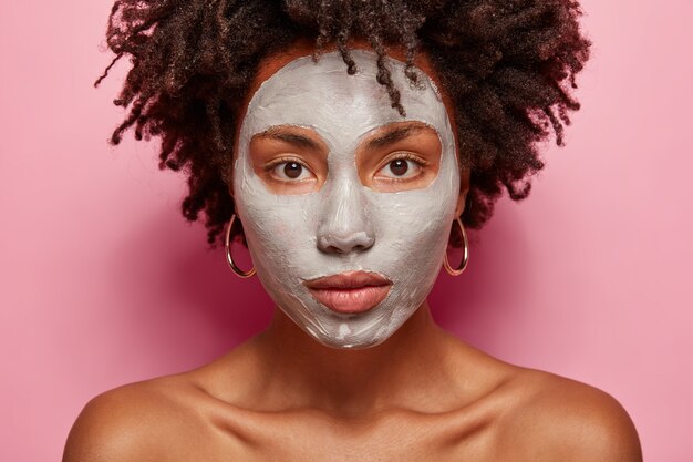 Porträt der jungen Frau mit Afro-Haarschnitt und Gesichtsmaske