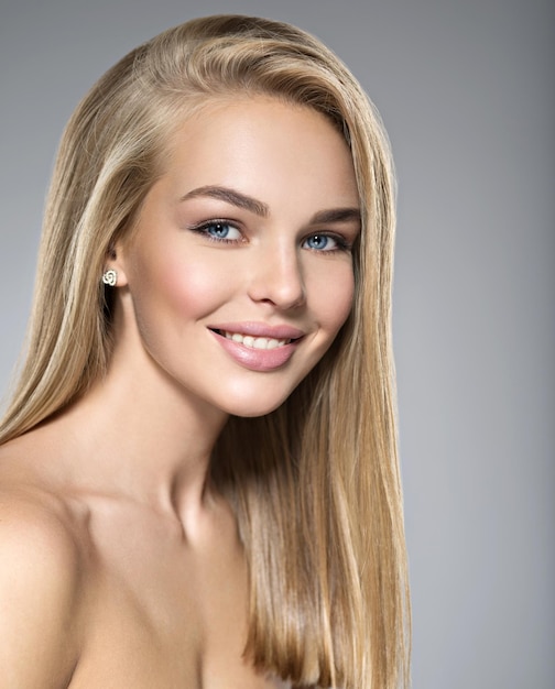 Porträt der jungen Frau mit dem schönen Lächeln. Hübsches wunderschönes Mädchen mit langen hellen glatten Haaren und braunem Make-up. Gesicht eines Modells blaue Augen. posieren